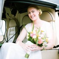 Glückliche Braut mit Blumenstrauß sitzt im Helikopter.