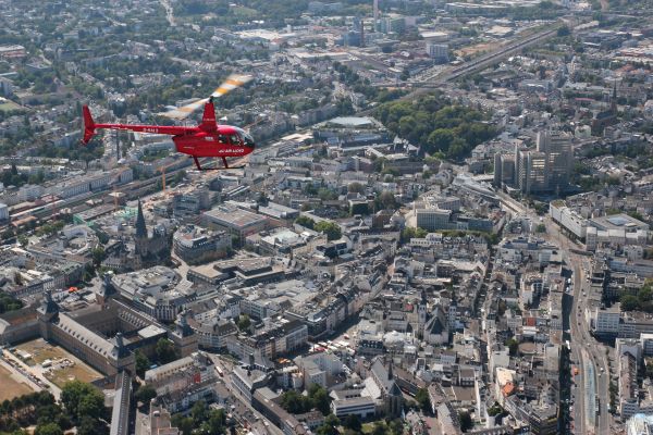 Ein roter Hubschrauber macht einen Rundflug über Köln.