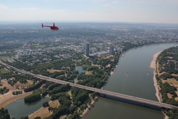Roter Helikopter macht einen Rundflug über den Rhein in Köln.