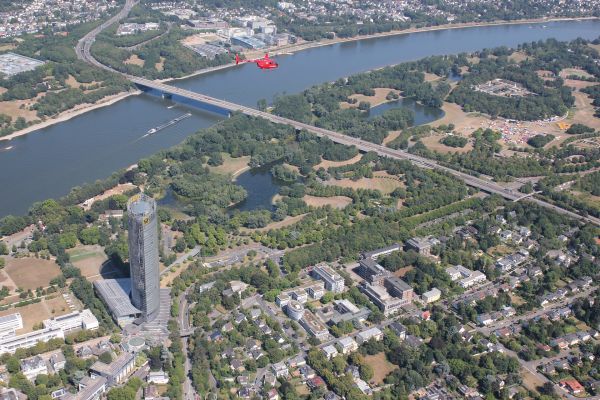 Ein roter Helikopter der über den Rheintal in Köln fliegt.