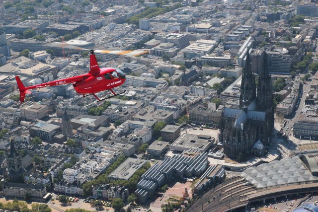Roter AirLloyd Helikopter macht einen Rundflug über Köln.