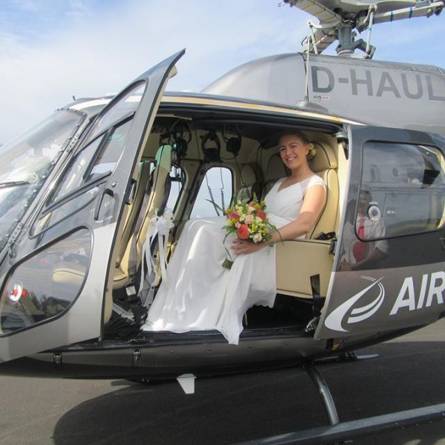 Bride sits happily in a black AirLloyd helicopter.