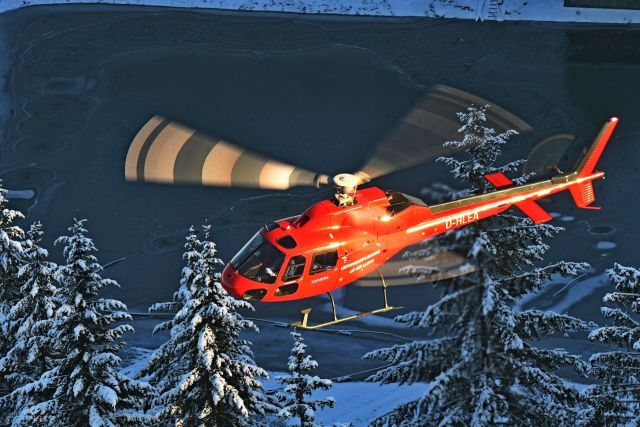 Ein roter Hubschrauber fliegt über einen zugefrorenen See.