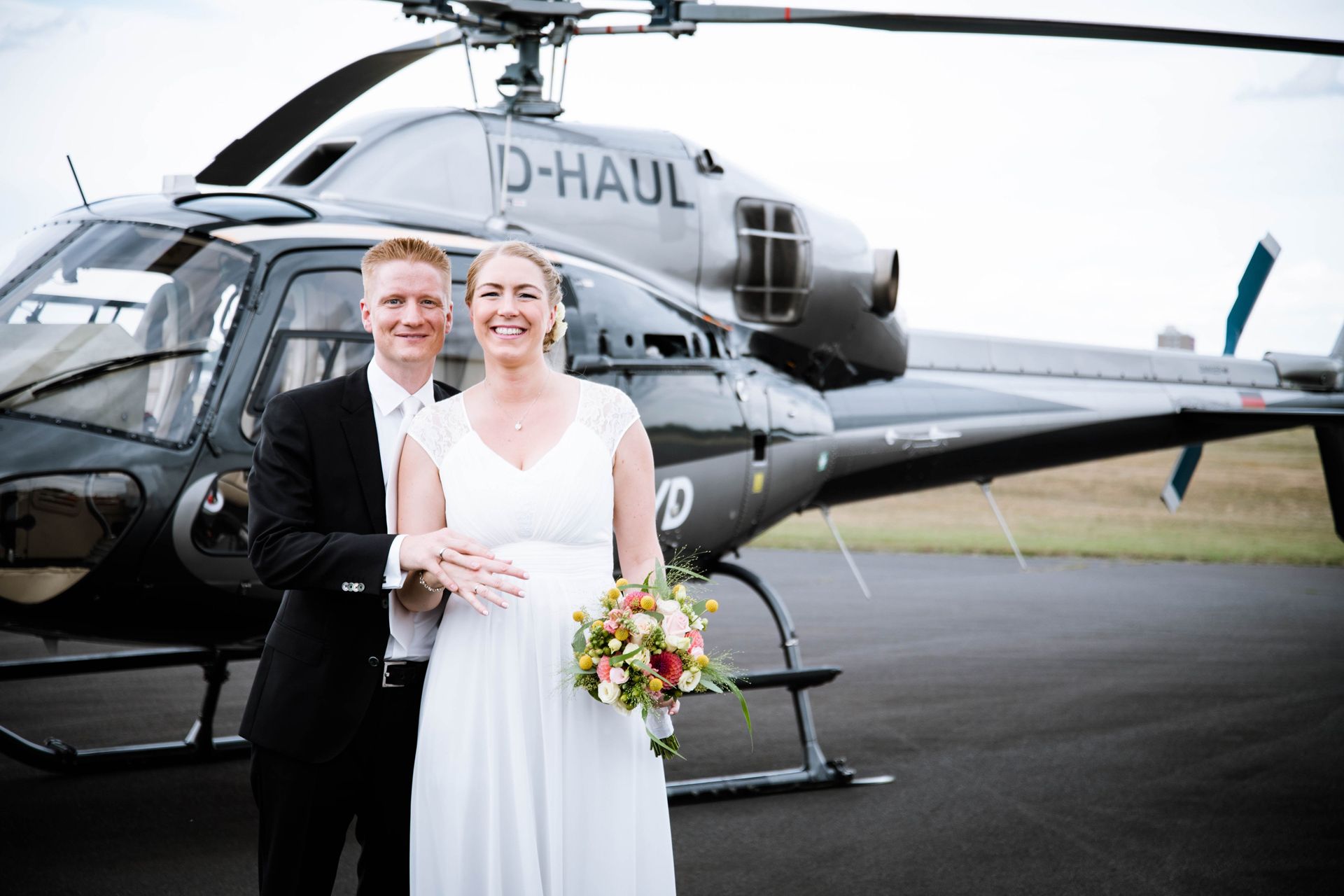 A bridal couple in front of a black helicopter.