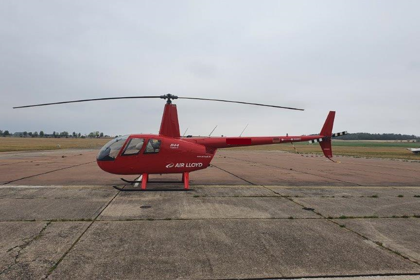 A red Air Lloyd helicopter on the landing pad