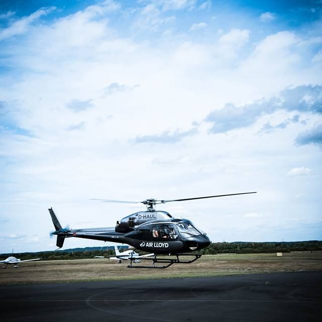 Ein schwarzer AirLloyd Hubschrauber startet auf einem Landeplatz.