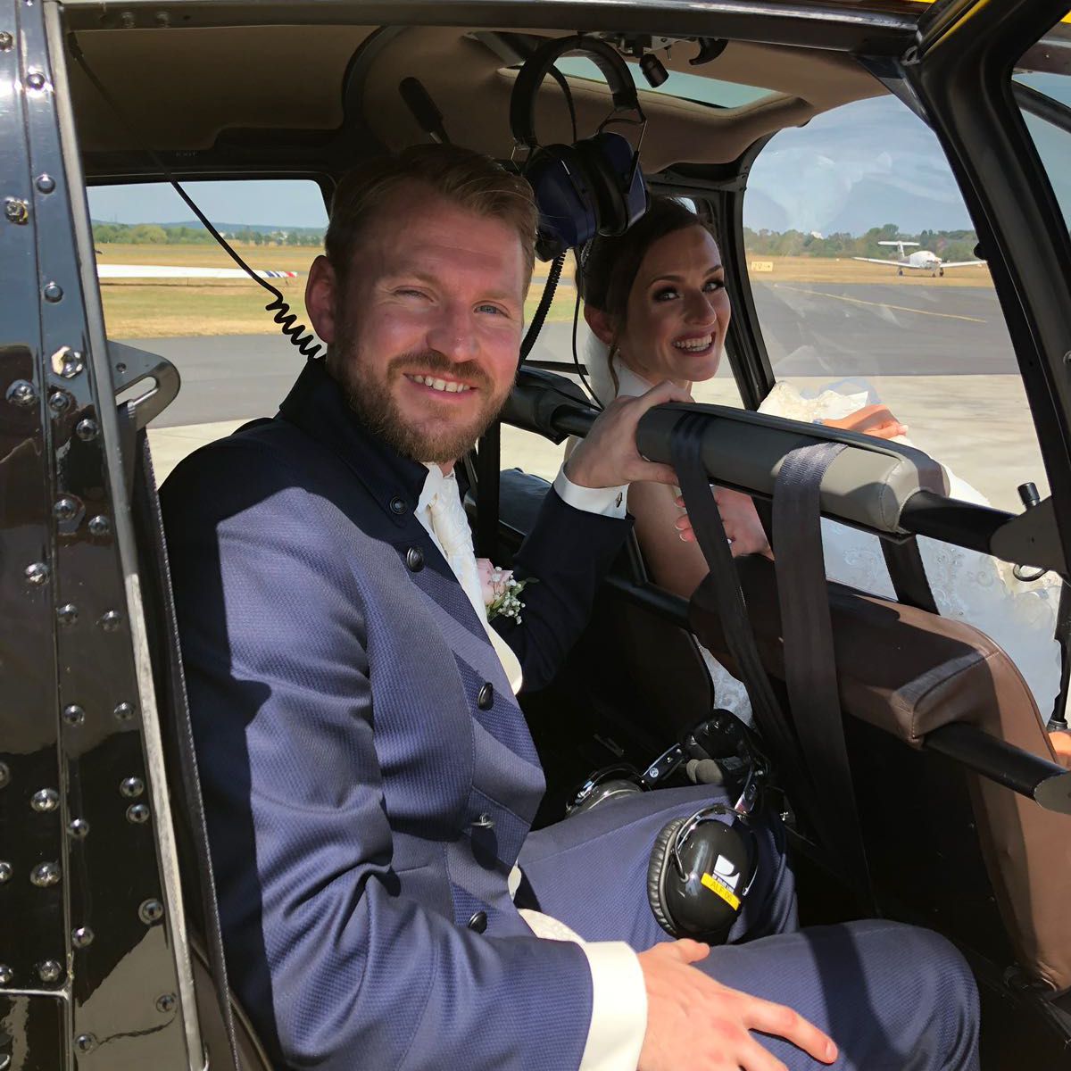 A happy bridal couple sits in a helicopter.