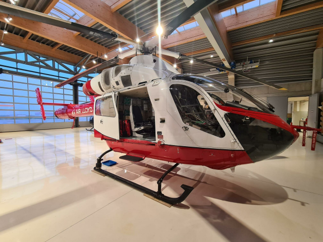 Ein rot-weißer AirLloyd Hubschrauber im Hangar.