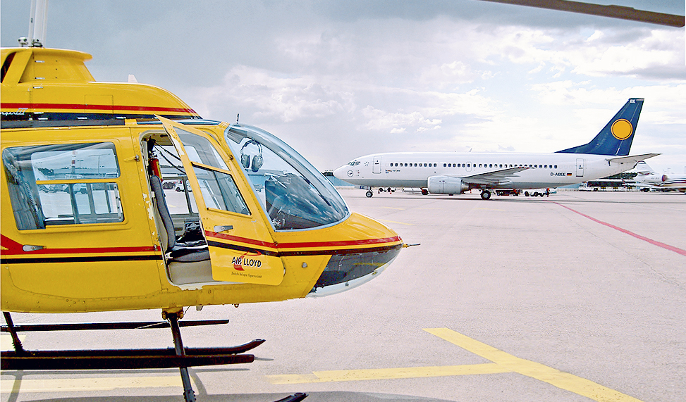 A yellow Air Lloyd helicopter and a large airplane