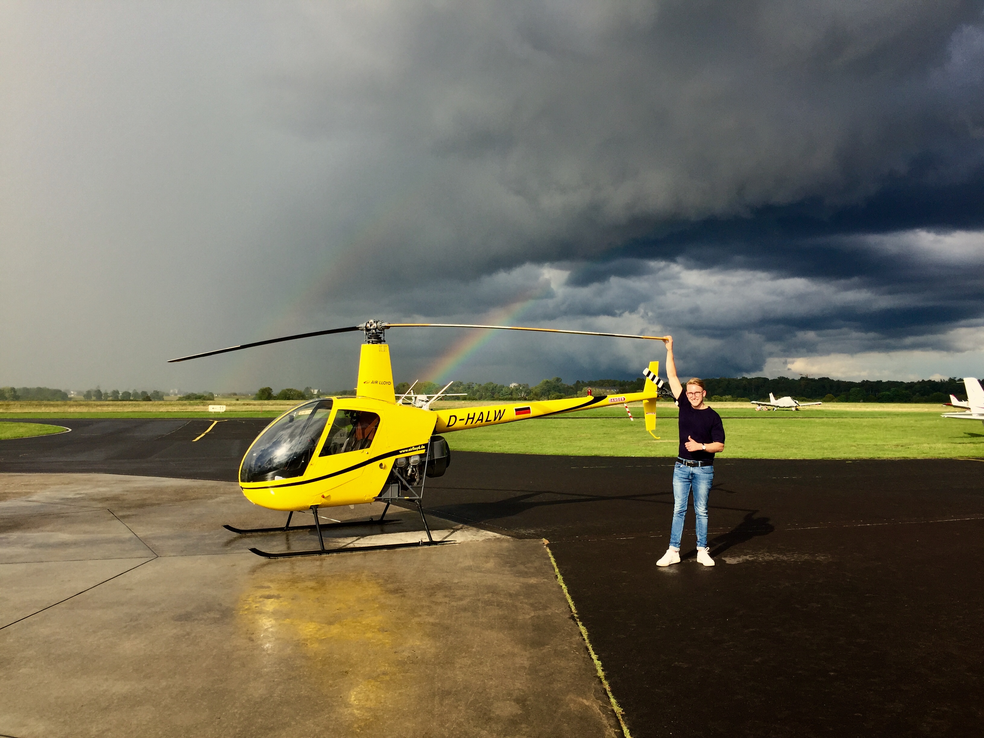 Ein Mann steht neben einem gelben Helikopter.